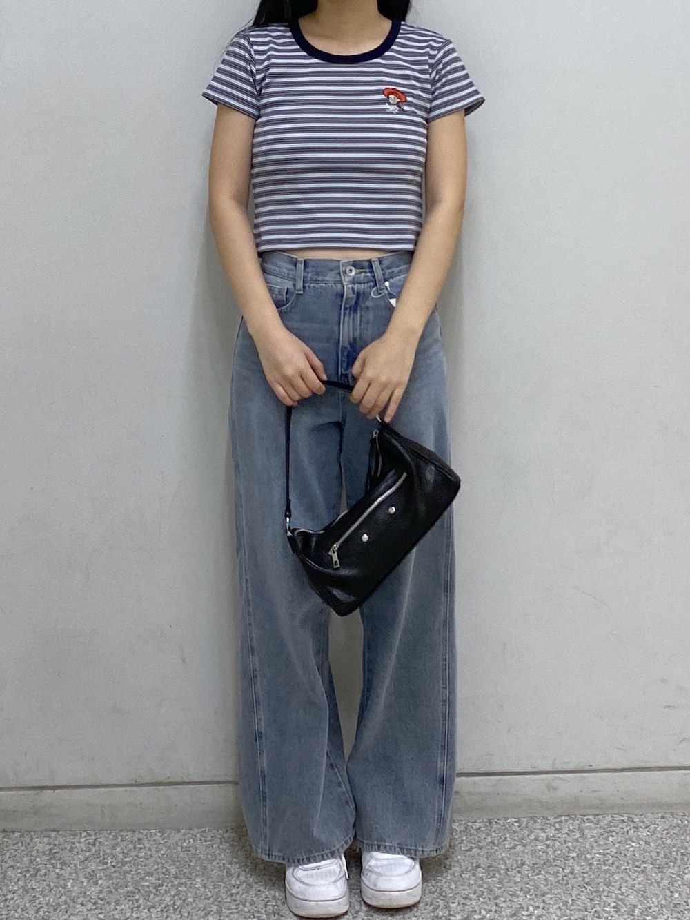 ブラック系のショルダーバッグ、ブルー系のデニムパンツ、ブルー系のTシャツ/カットソーを着用したレディースの夏コーディネートの2枚目の写真
