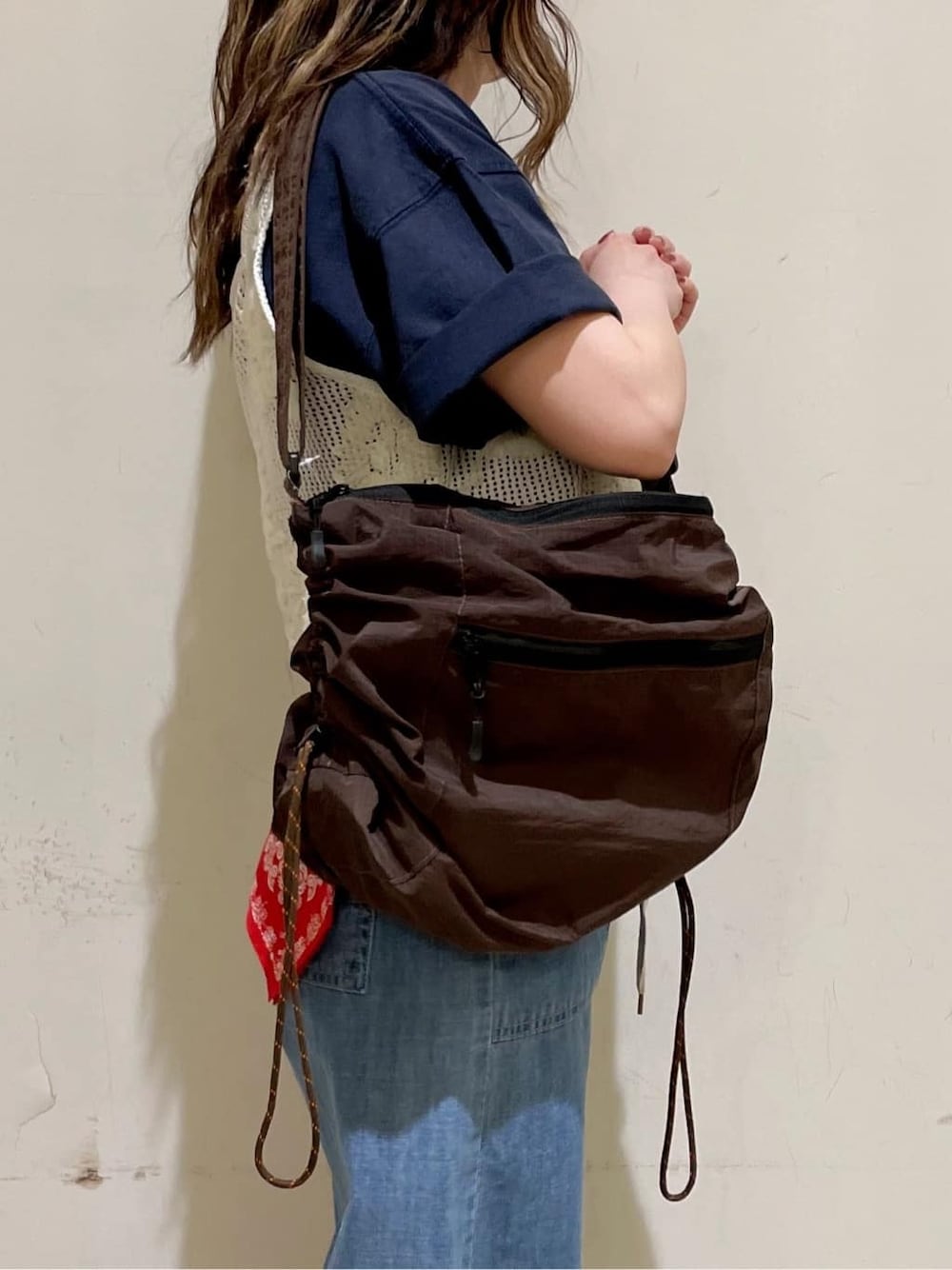 ブラウン系のショルダーバッグ、ブルー系のTシャツ/カットソー、ホワイト系のベストを着用したレディースの春コーディネートの3枚目の写真