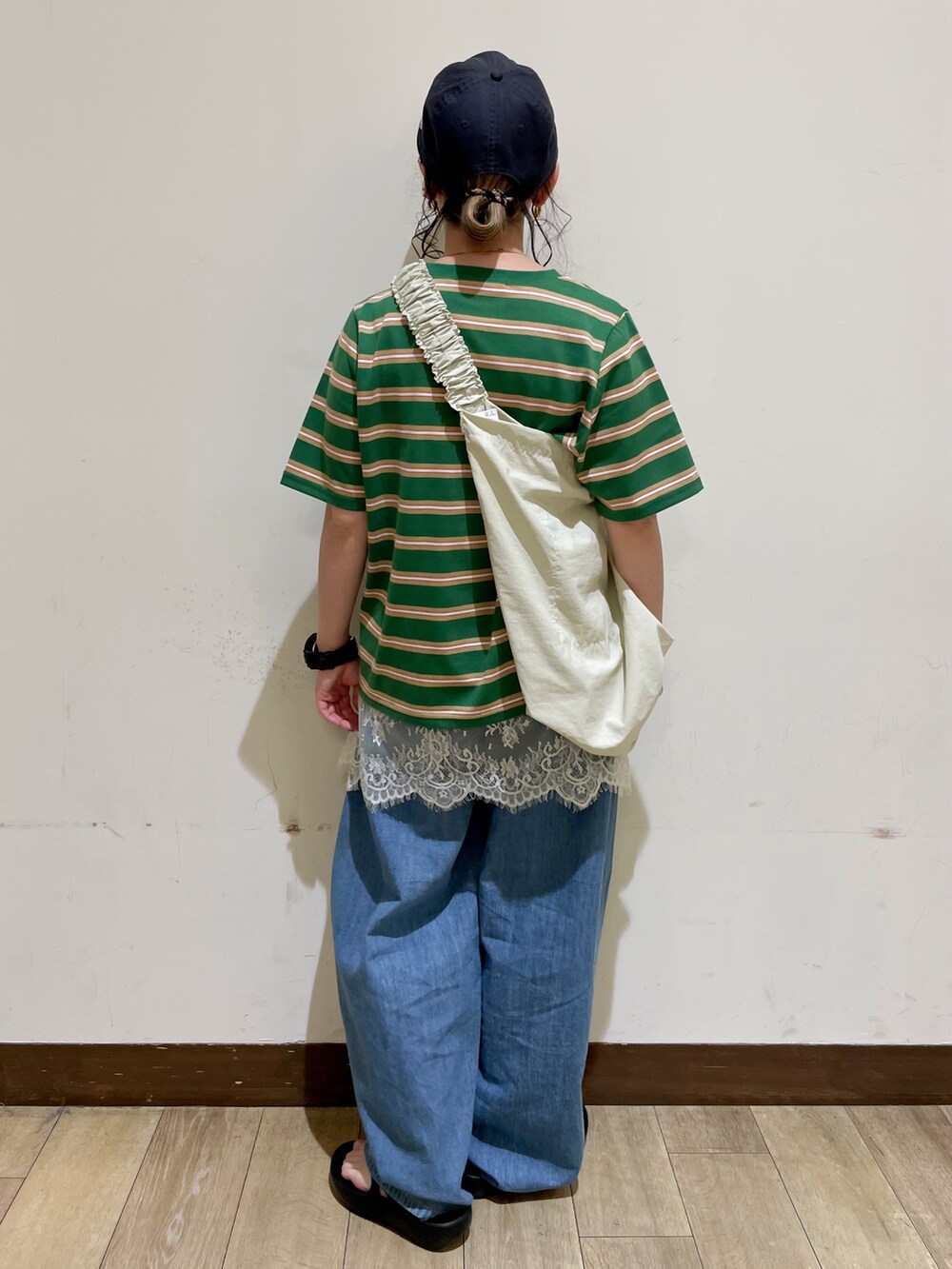 ブルー系のデニムパンツ、ベージュ系のショルダーバッグ、ブラック系のサンダルを着用したレディースの夏コーディネートの2枚目の写真