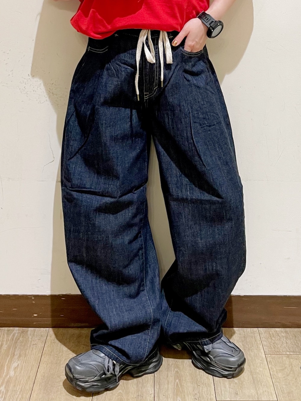 レッド系のTシャツ/カットソー、ブルー系のデニムパンツ、グリーン系のショルダーバッグを着用したレディースの夏コーディネートの7枚目の写真