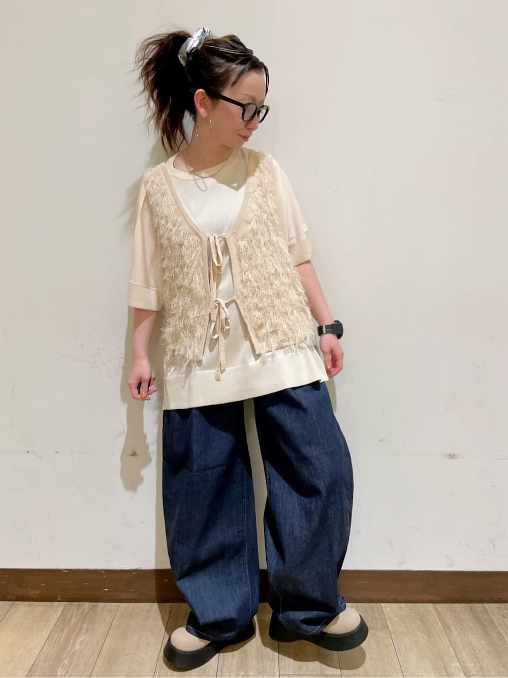 ホワイト系のベスト、ホワイト系のニット/セーター、ブルー系のデニムパンツを着用したレディースの春コーディネートの6枚目の写真