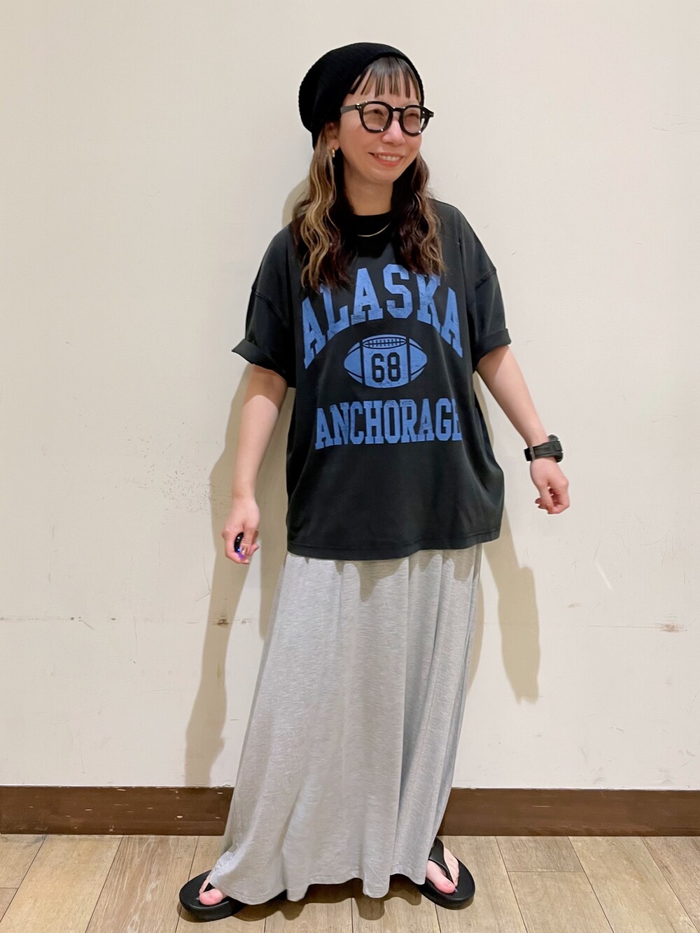 グレー系のTシャツ/カットソー、グレー系のスカート、ブラック系のサンダルを着用したレディースの夏コーディネートの6枚目の写真