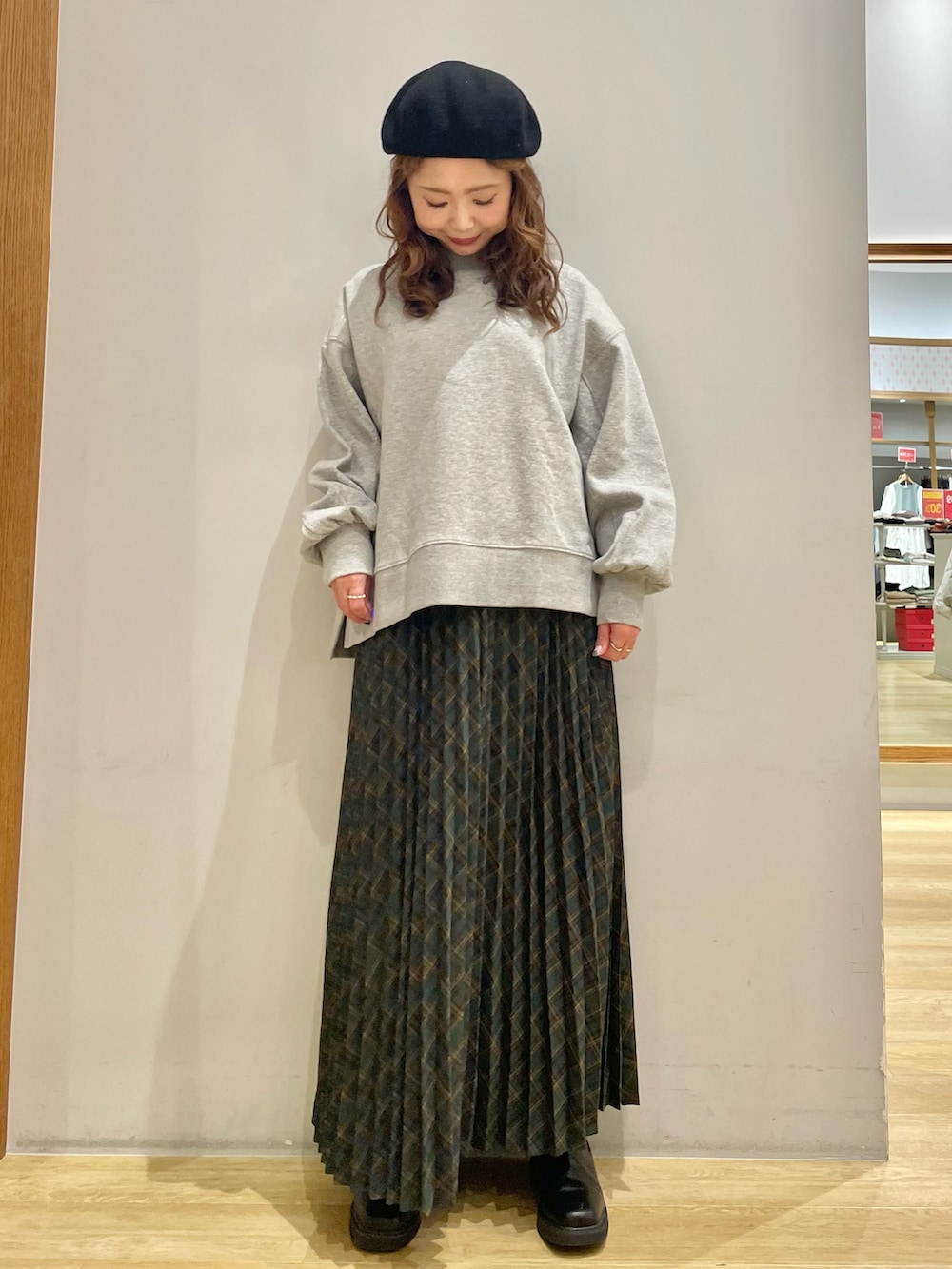 グレー系のスウェット、グリーン系のスカート、ブラック系のブーツを着用したレディースの冬コーディネートの2枚目の写真