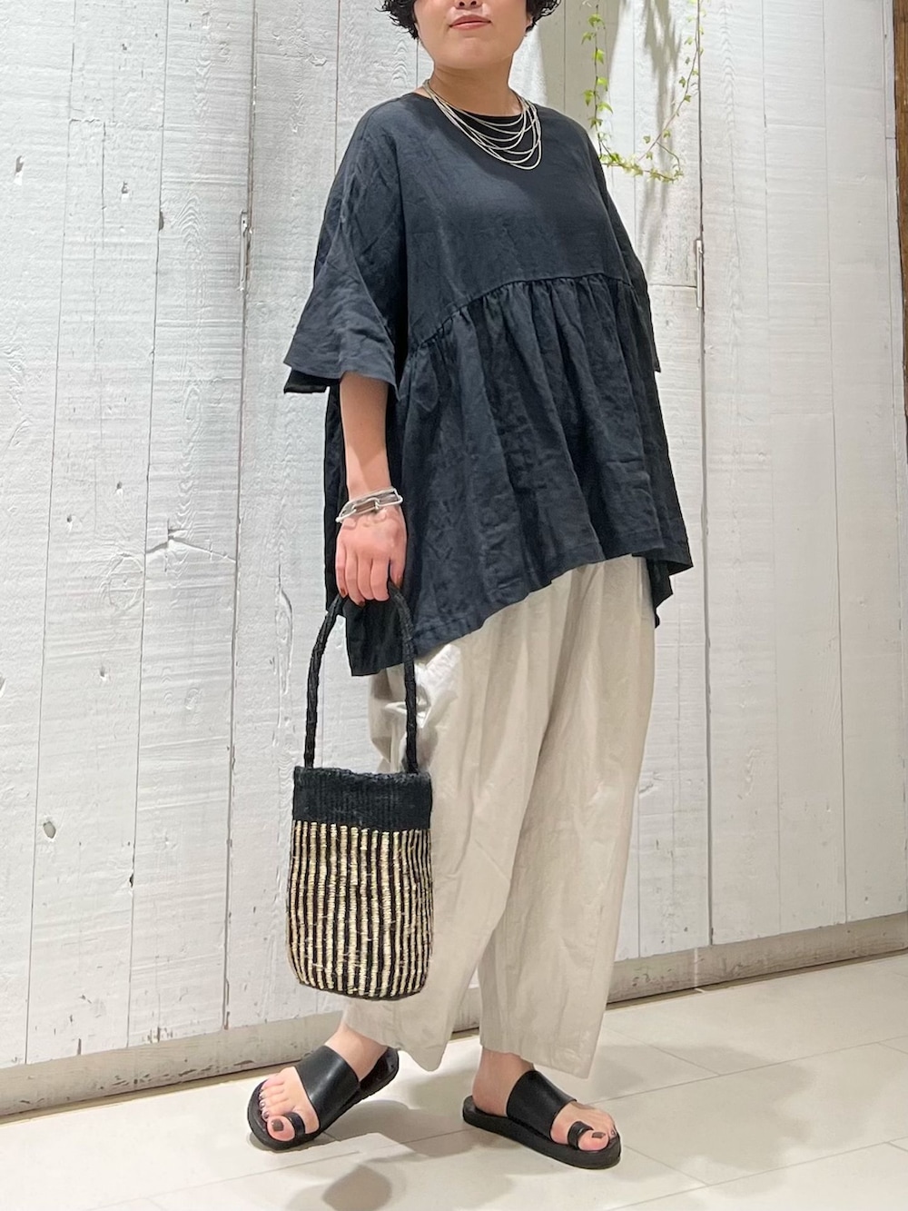 グレー系のその他パンツ、ブラック系のシャツ/ブラウス、ブラック系のかごバッグを着用したレディースの夏コーディネートの3枚目の写真