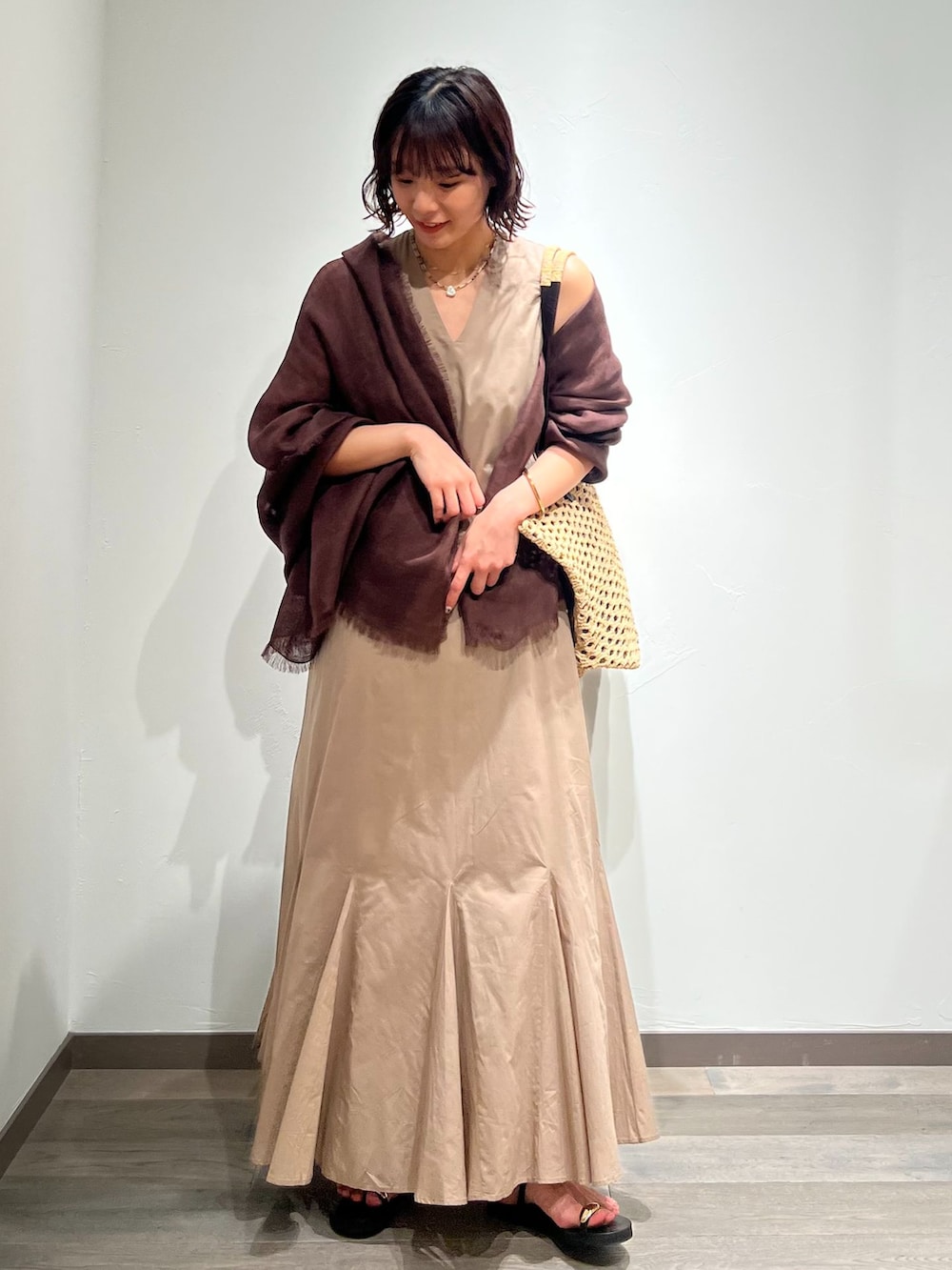 ベージュ系のワンピース、ベージュ系のトートバッグ、ブラック系のサンダルを着用したレディースの春コーディネートの4枚目の写真
