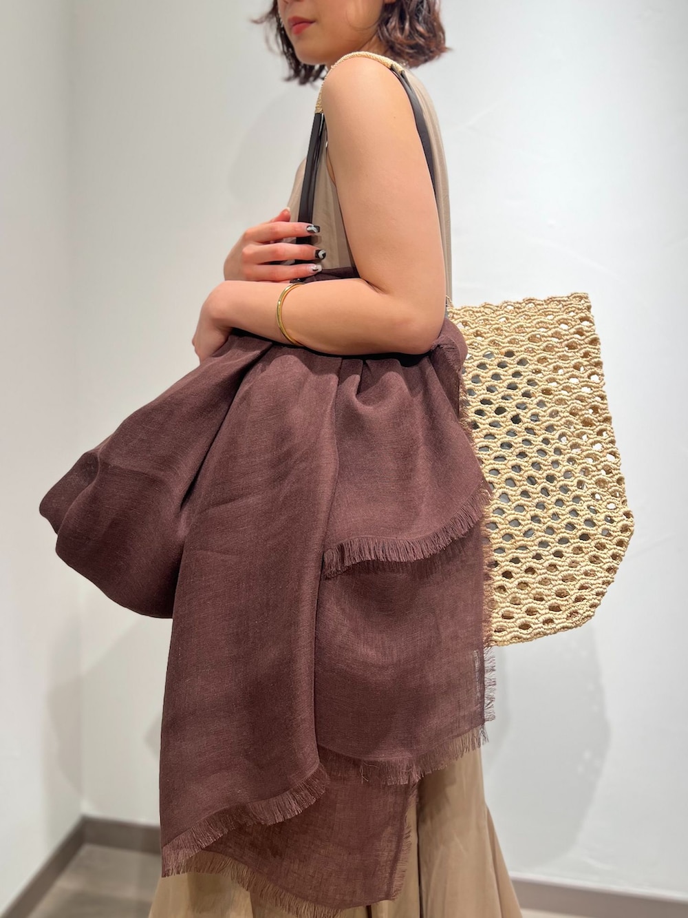ベージュ系のワンピース、ベージュ系のトートバッグ、ブラック系のサンダルを着用したレディースの春コーディネートの6枚目の写真