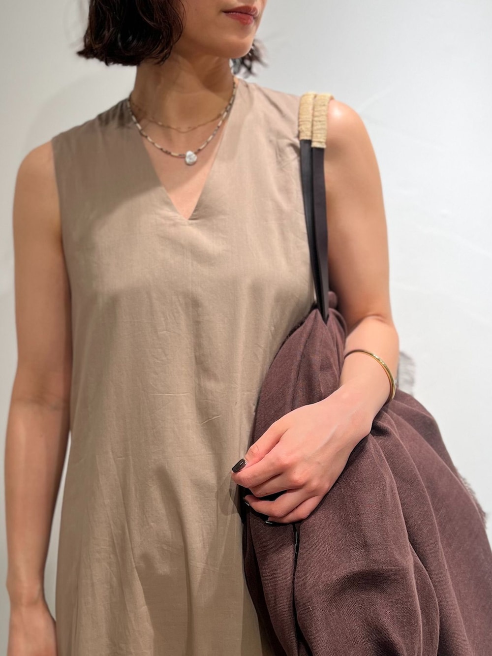 ベージュ系のワンピース、ベージュ系のトートバッグ、ブラック系のサンダルを着用したレディースの春コーディネートの7枚目の写真