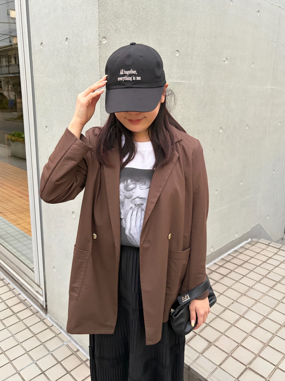 ホワイト系のTシャツ/カットソー、ブラウン系のテーラードジャケット、ブラック系のスカートを着用したレディースの春コーディネートの3枚目の写真