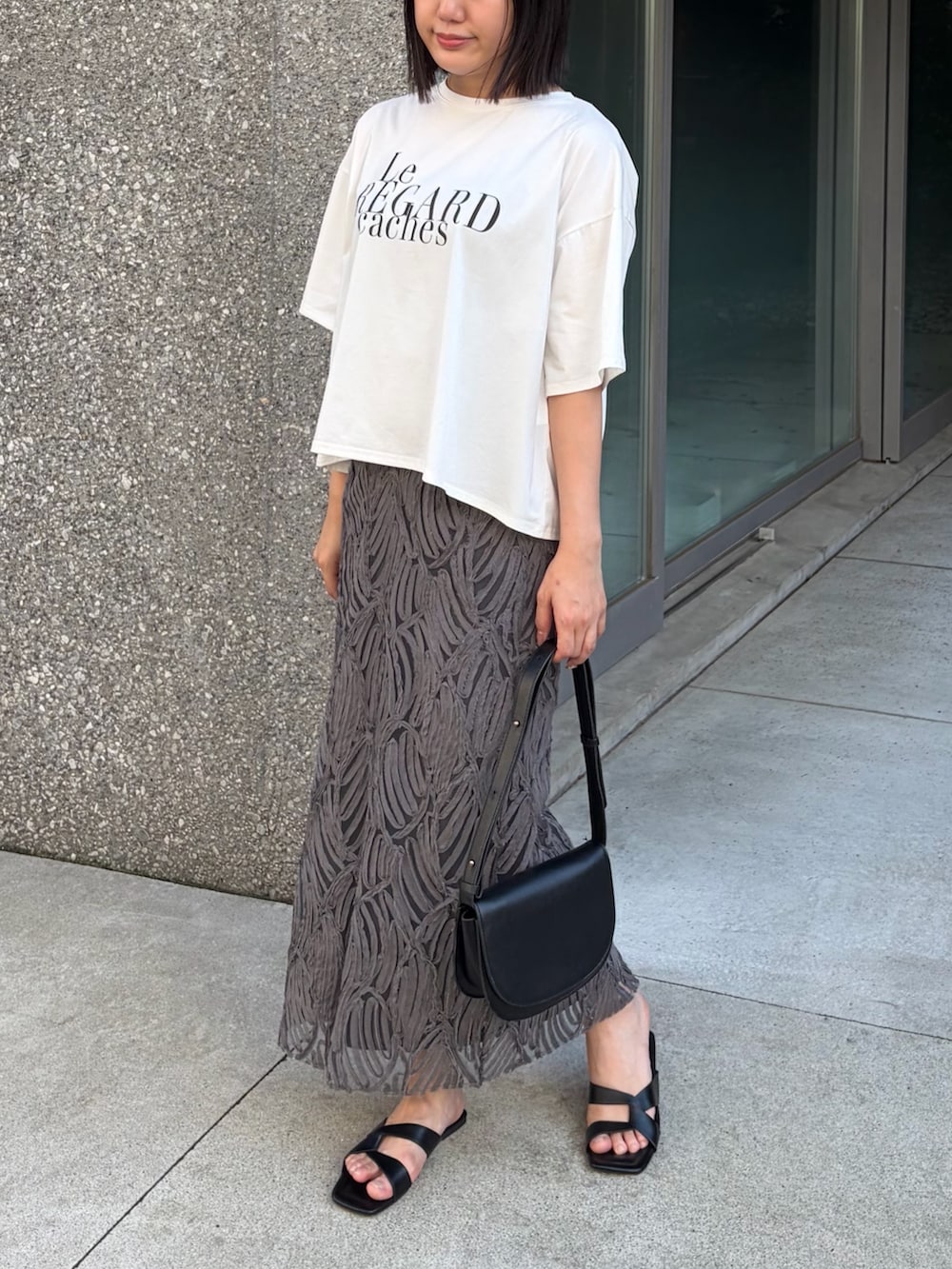 ホワイト系のTシャツ/カットソー、グレー系のスカート、ブラック系のサンダルを着用したレディースの夏コーディネートの2枚目の写真