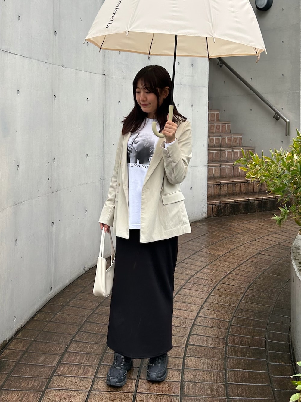 ベージュ系のテーラードジャケット、ホワイト系のTシャツ/カットソー、ブラック系のスカートを着用したレディースの春コーディネートの2枚目の写真