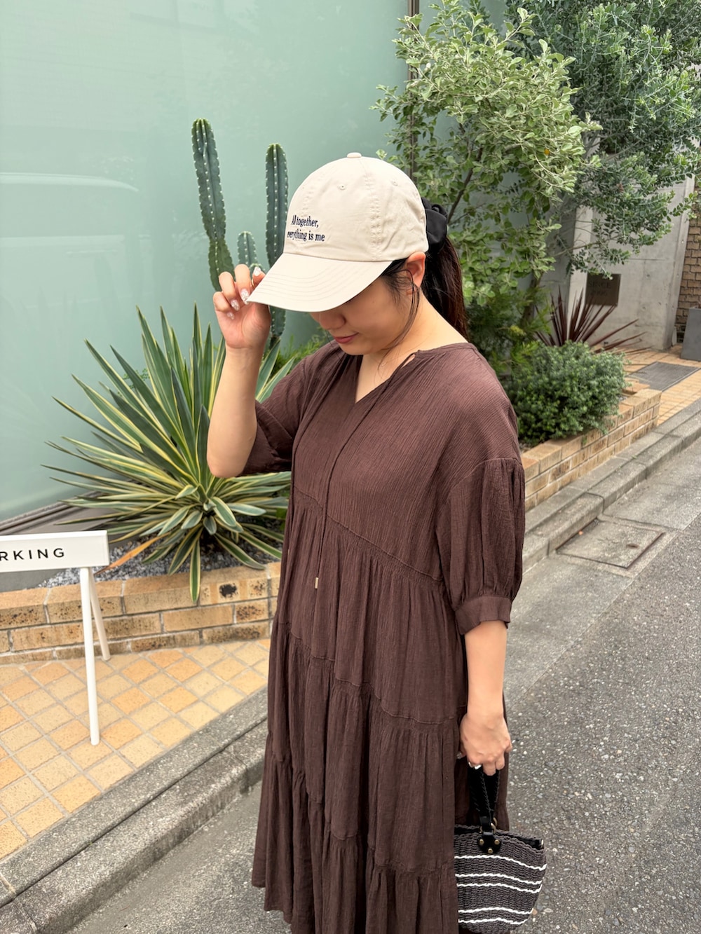 ブラウン系のワンピース、ブラック系のサンダル、ベージュ系のキャップを着用したレディースの夏コーディネートの4枚目の写真