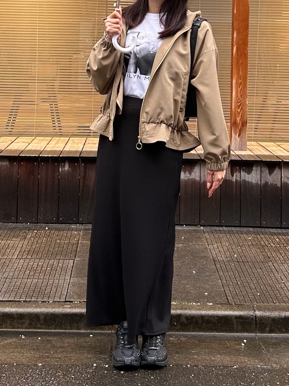 ベージュ系のマウンテンパーカー、ホワイト系のTシャツ/カットソー、ブラック系のスカートを着用したレディースの春コーディネートの3枚目の写真