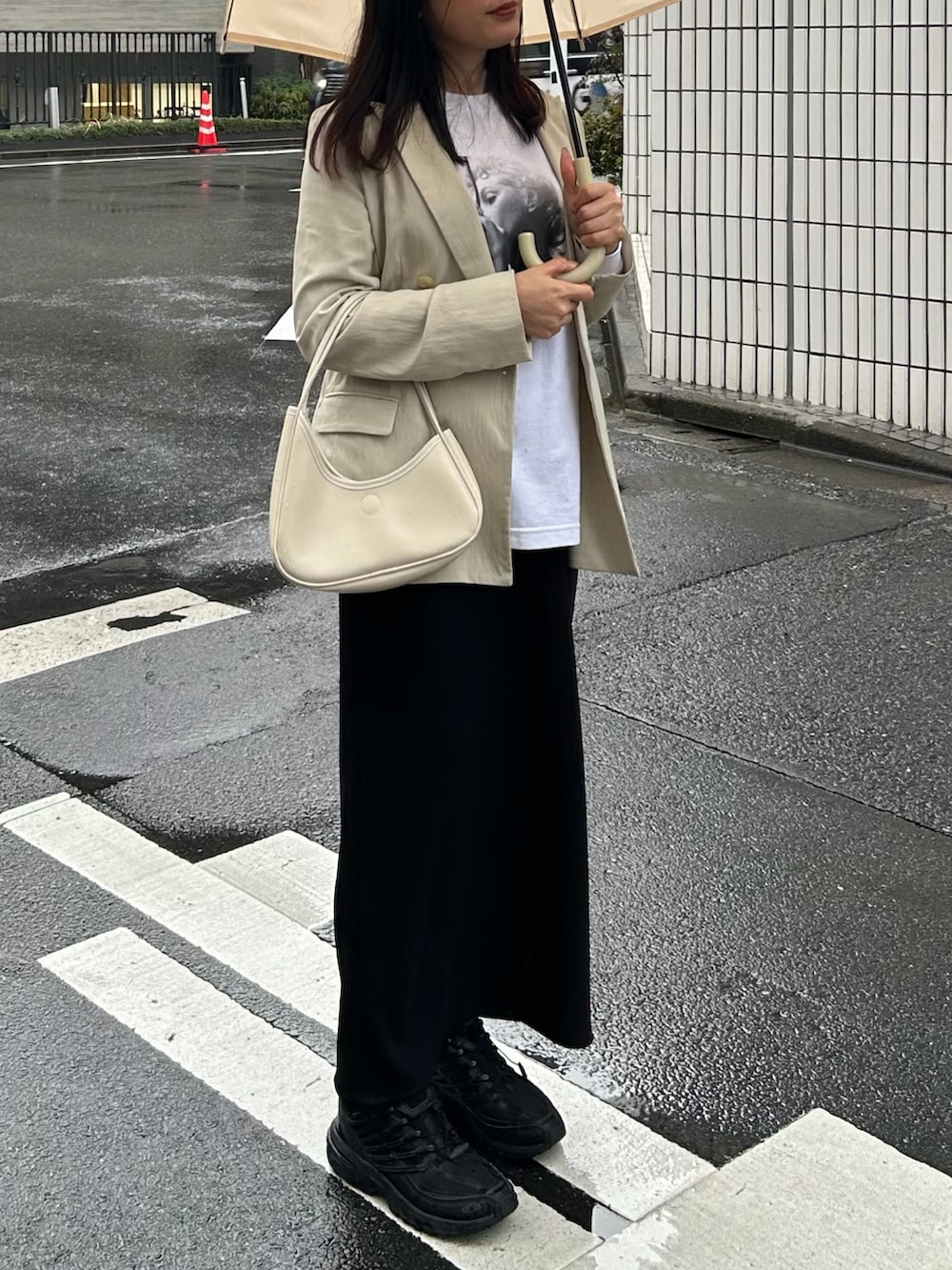 ベージュ系のテーラードジャケット、ホワイト系のTシャツ/カットソー、ブラック系のスカートを着用したレディースの春コーディネートの3枚目の写真
