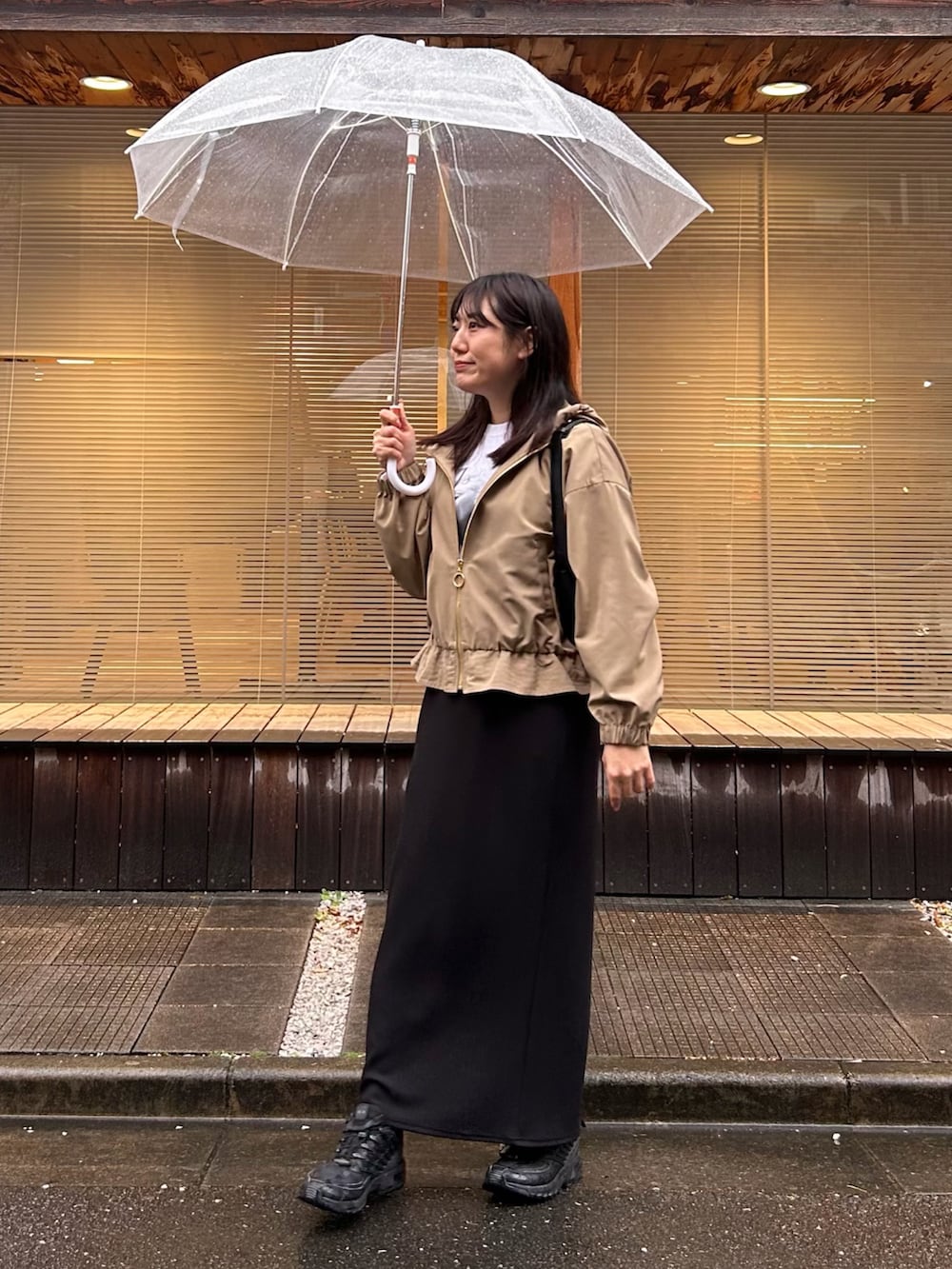 ベージュ系のマウンテンパーカー、ホワイト系のTシャツ/カットソー、ブラック系のスカートを着用したレディースの春コーディネートの2枚目の写真