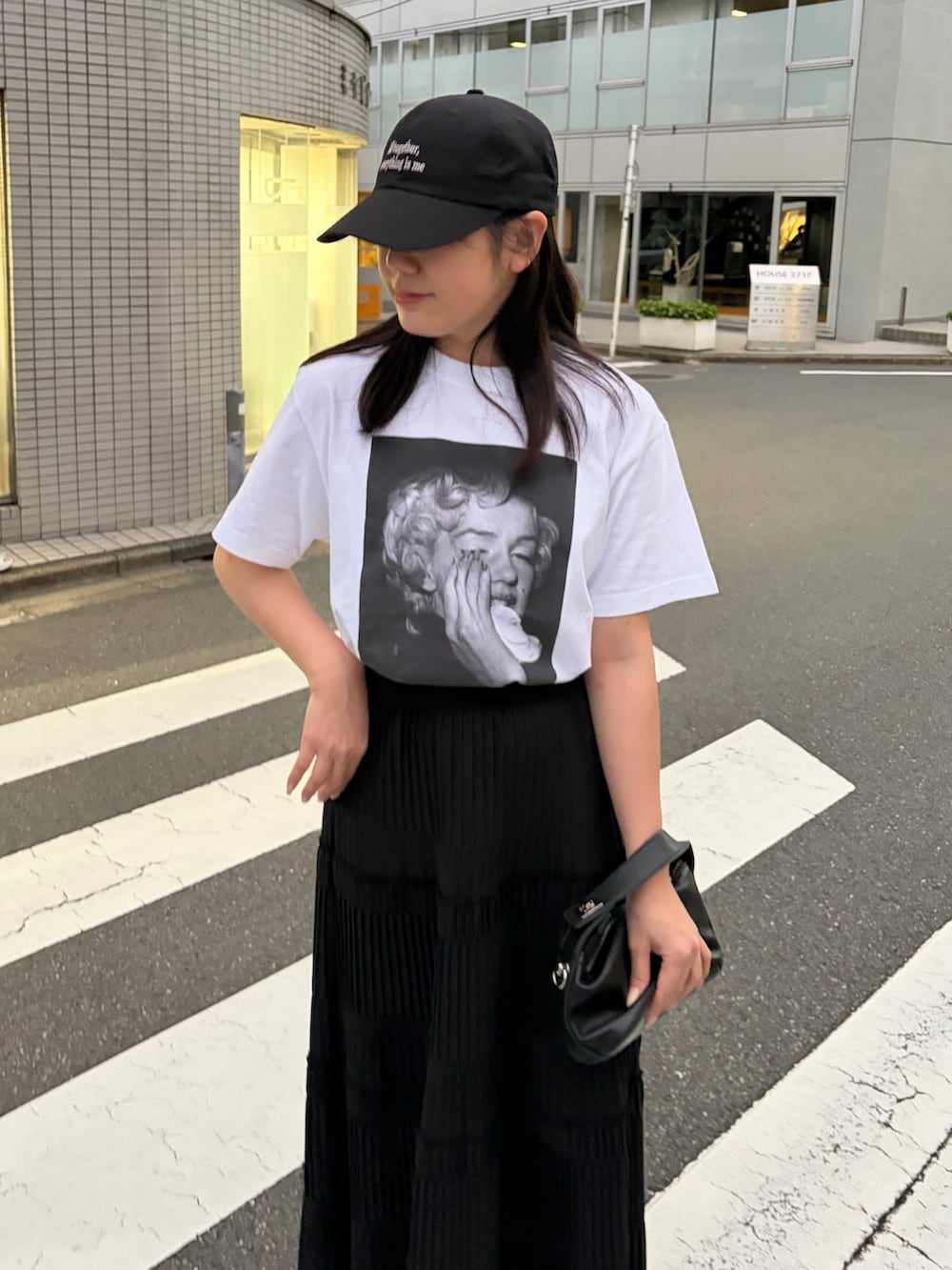 ホワイト系のTシャツ/カットソー、ブラック系のスカート、ブラック系のサンダルを着用したレディースの春コーディネートの2枚目の写真