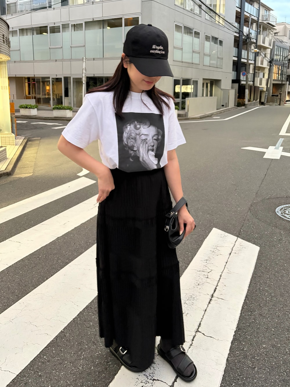 ホワイト系のTシャツ/カットソー、ブラック系のスカート、ブラック系のサンダルを着用したレディースの春コーディネートの3枚目の写真