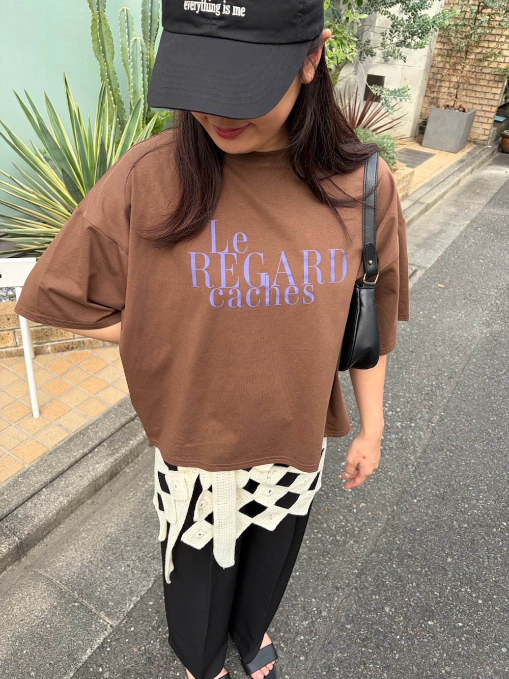 ブラック系のスラックス、ブラウン系のTシャツ/カットソー、ホワイト系のスカートを着用したレディースの夏コーディネートの3枚目の写真