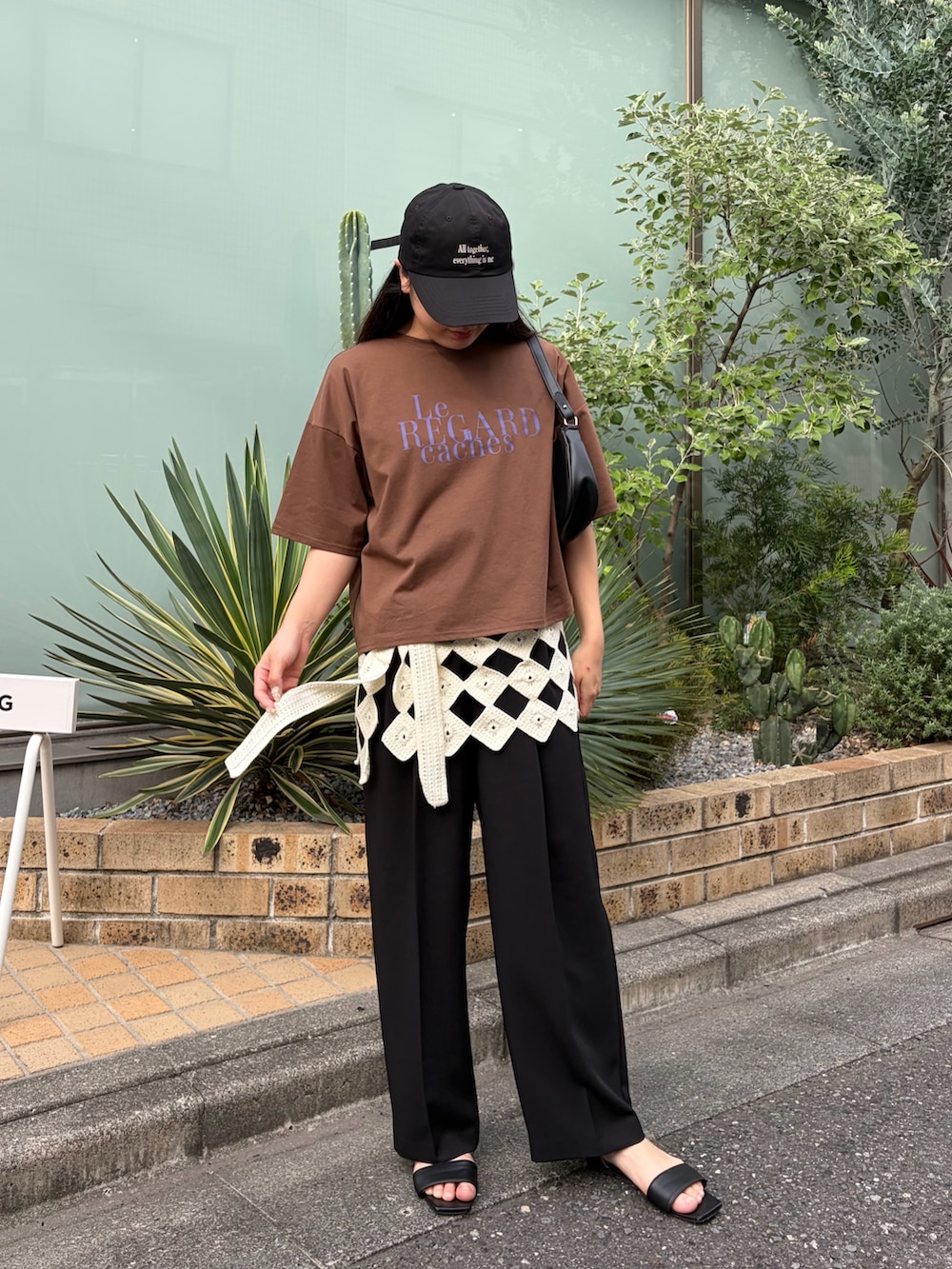 ブラック系のスラックス、ブラウン系のTシャツ/カットソー、ホワイト系のスカートを着用したレディースの夏コーディネートの2枚目の写真