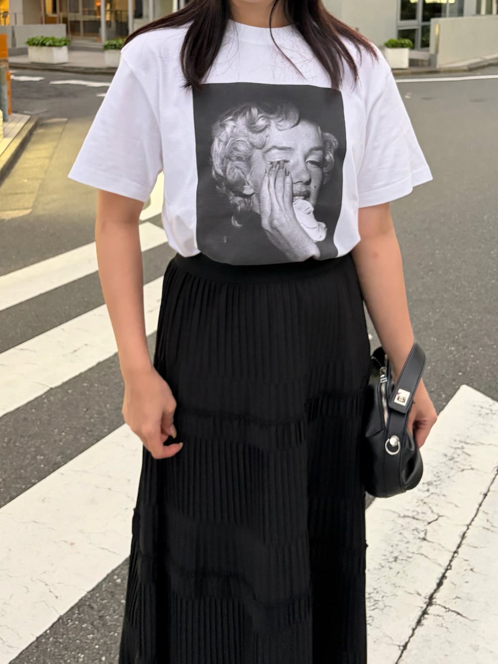 ホワイト系のTシャツ/カットソー、ブラック系のスカート、ブラック系のサンダルを着用したレディースの春コーディネートの4枚目の写真