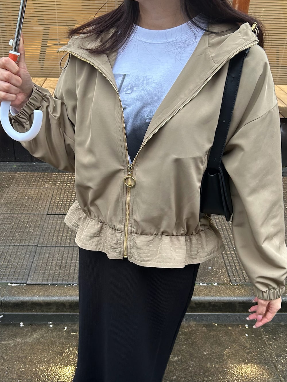 ベージュ系のマウンテンパーカー、ホワイト系のTシャツ/カットソー、ブラック系のスカートを着用したレディースの春コーディネートの4枚目の写真