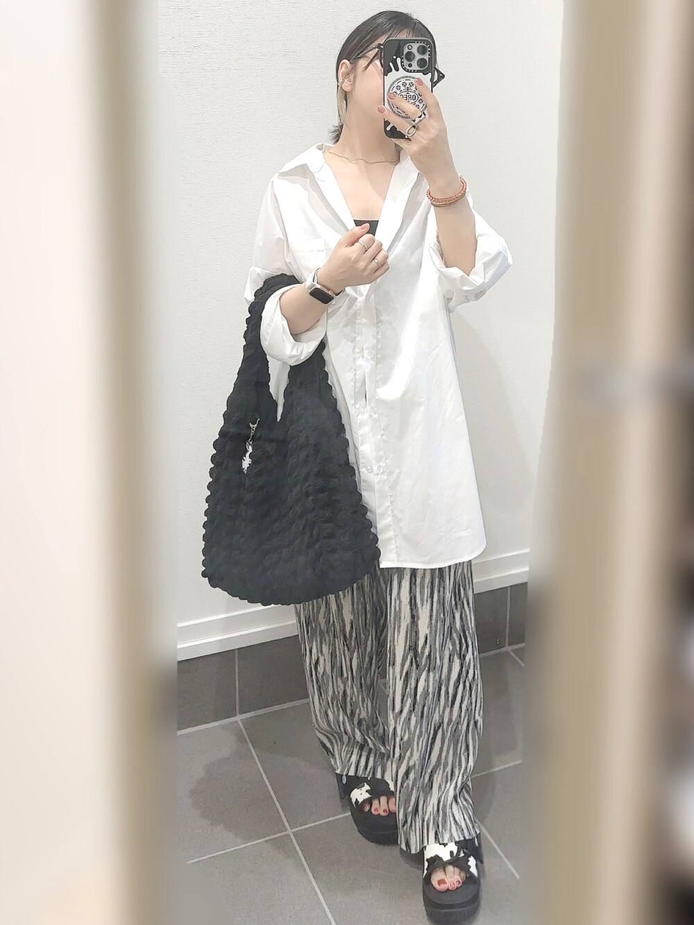 ブラック系のサンダル、グレー系のその他パンツ、ブラック系のトートバッグを着用したレディースの夏コーディネートの2枚目の写真