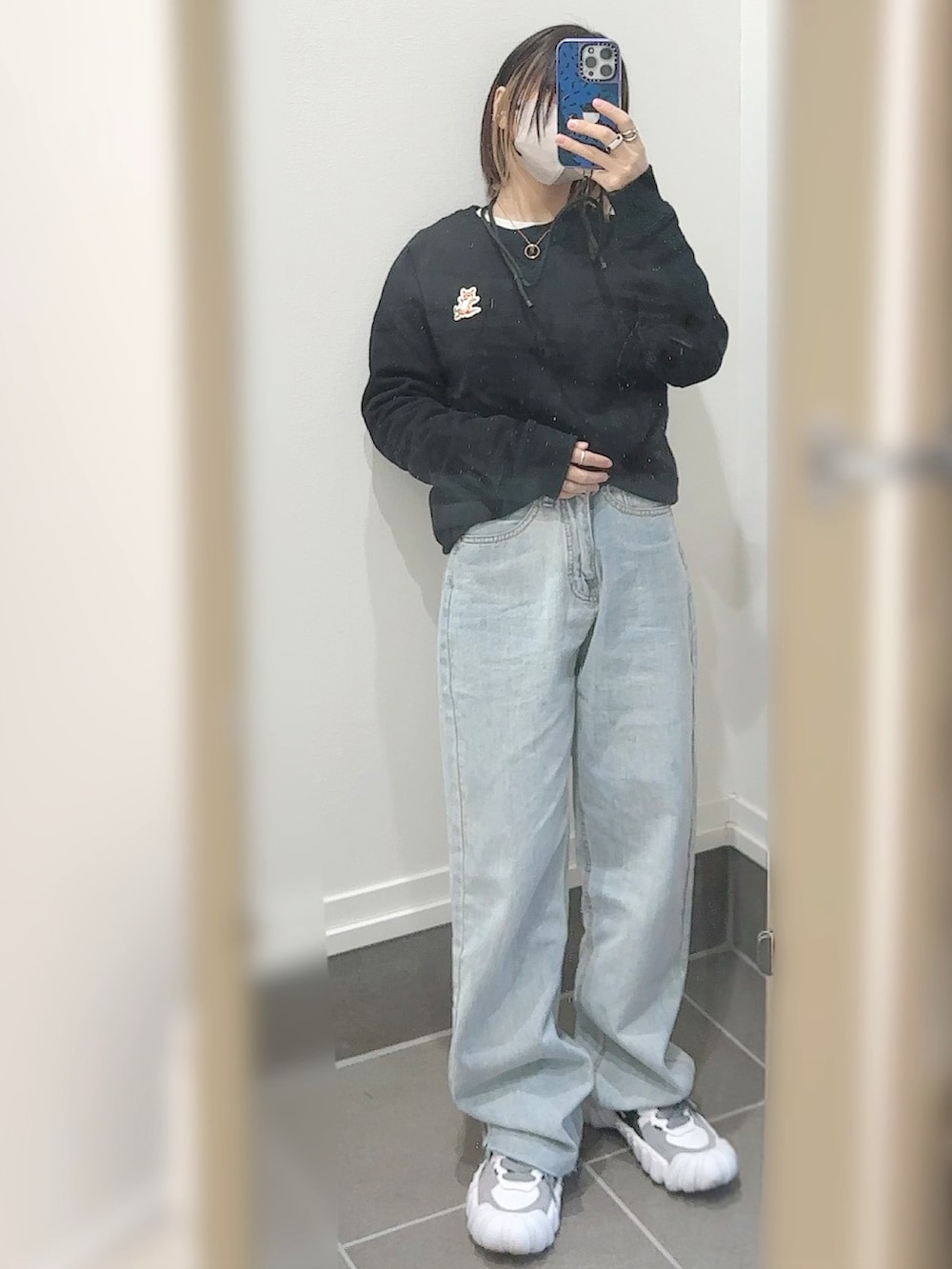 ブルー系のデニムパンツ、ホワイト系のスニーカー、ホワイト系のダウンベストを着用したレディースの冬コーディネートの2枚目の写真