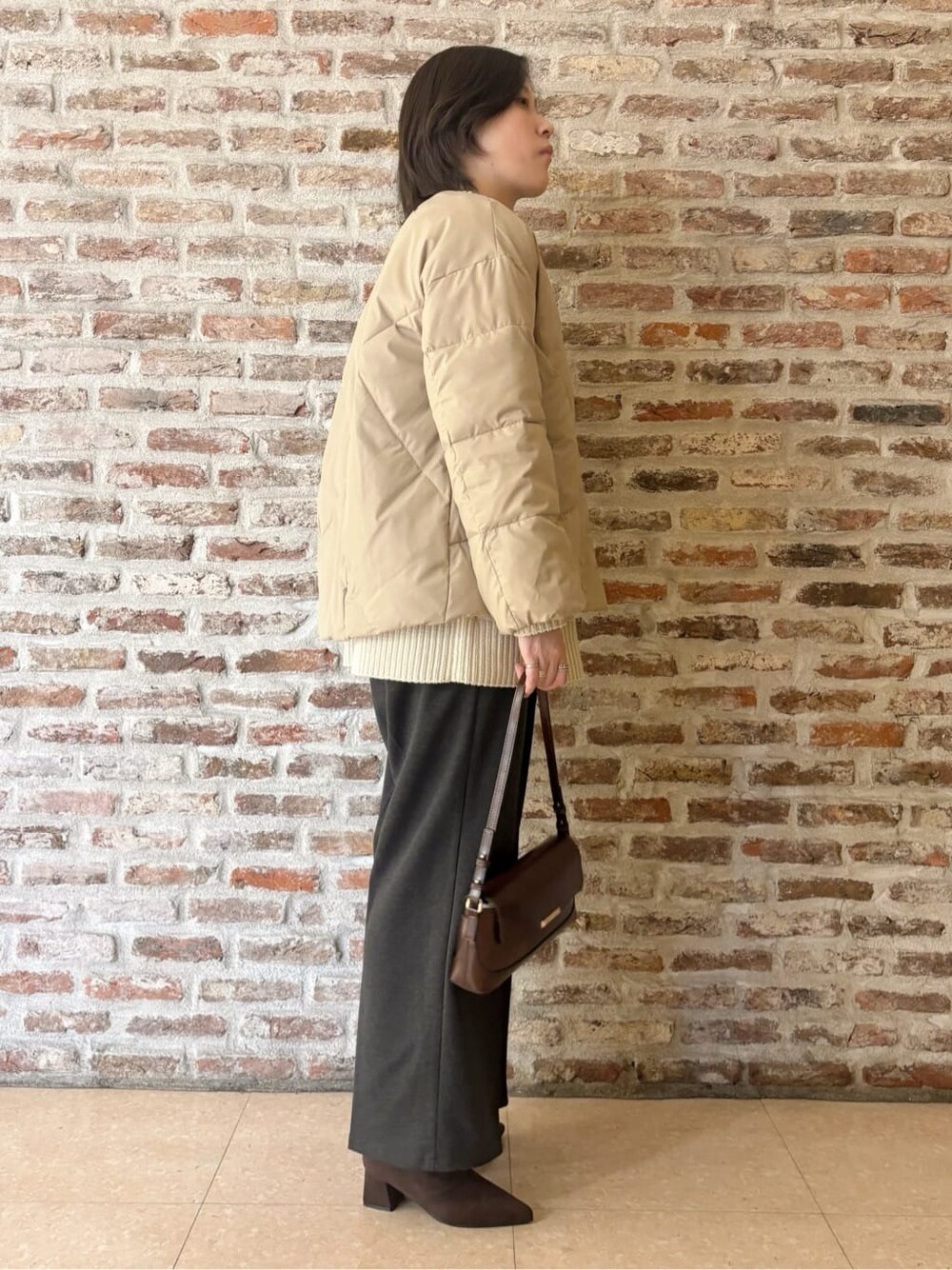ベージュ系のその他アウター、ホワイト系のニット/セーター、ブラック系のその他パンツを着用したレディースの冬コーディネートの4枚目の写真