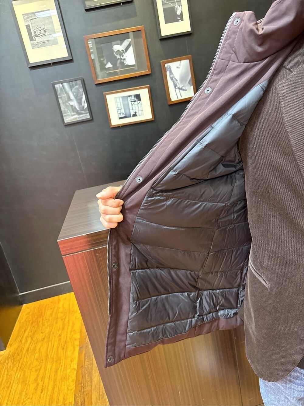 ブラウン系のダウンジャケット/コート、ブラウン系のテーラードジャケット、ブラック系のニット/セーターを着用したメンズの秋コーディネートの5枚目の写真