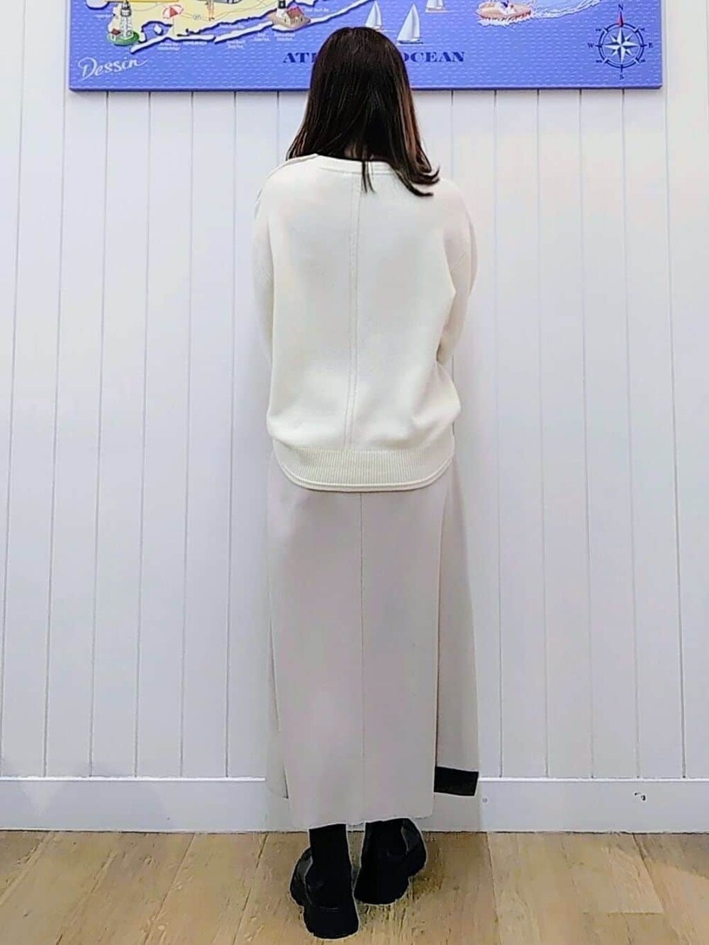 ホワイト系のニット/セーター、ベージュ系のスカート、ブラック系のブーツを着用したレディースの冬コーディネートの2枚目の写真