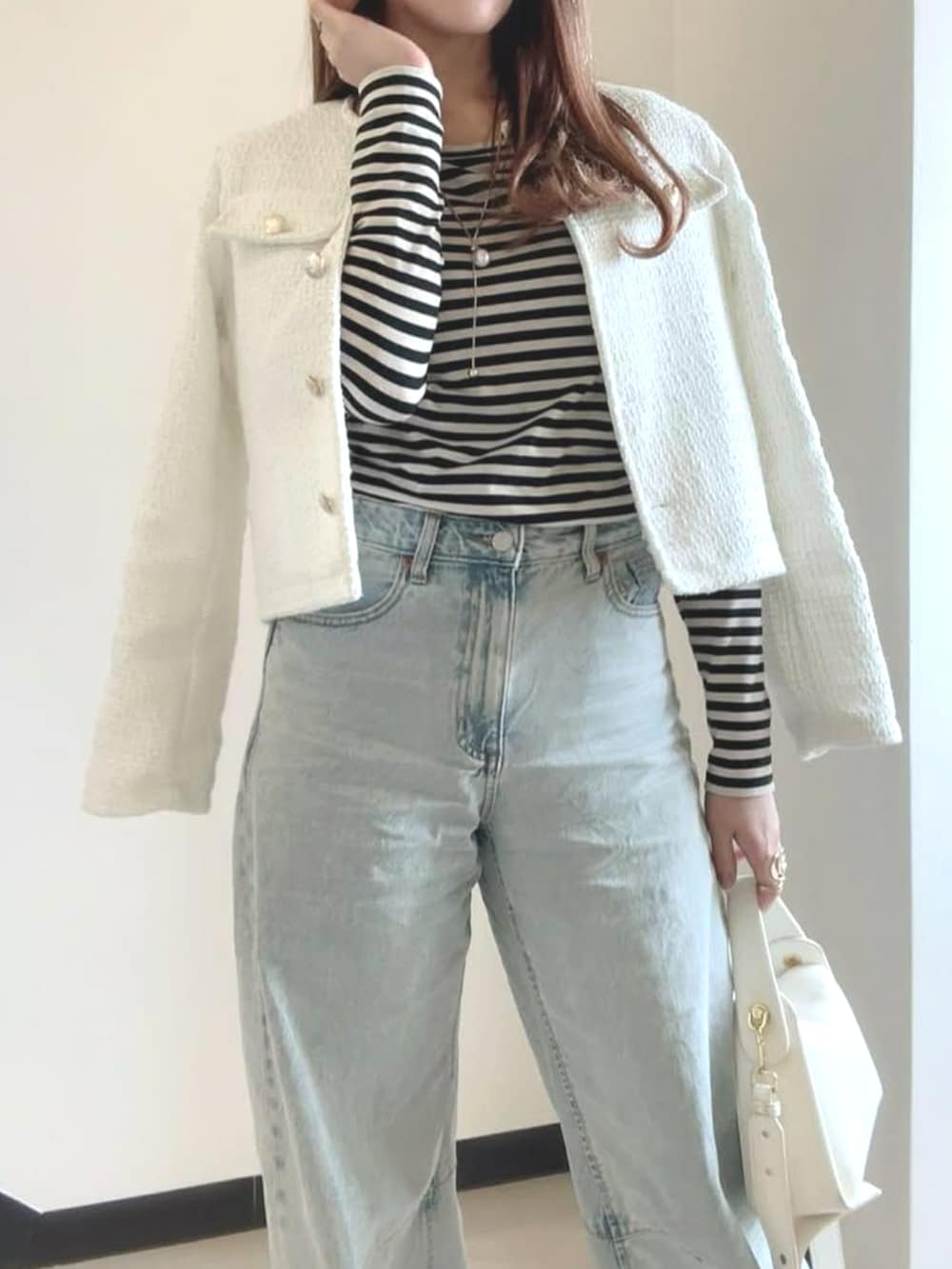 ホワイト系のノーカラージャケットを着用したレディースの冬コーディネートの3枚目の写真