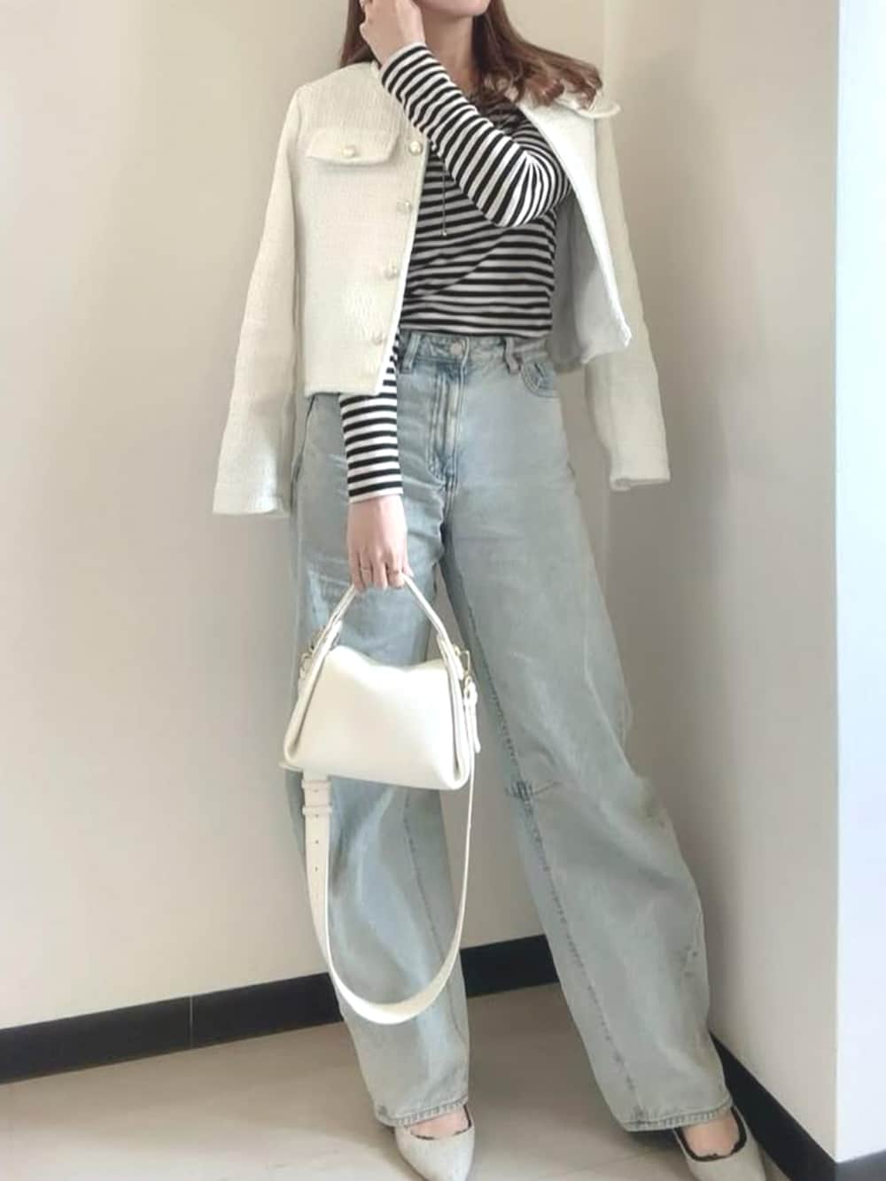 ホワイト系のノーカラージャケットを着用したレディースの冬コーディネートの2枚目の写真