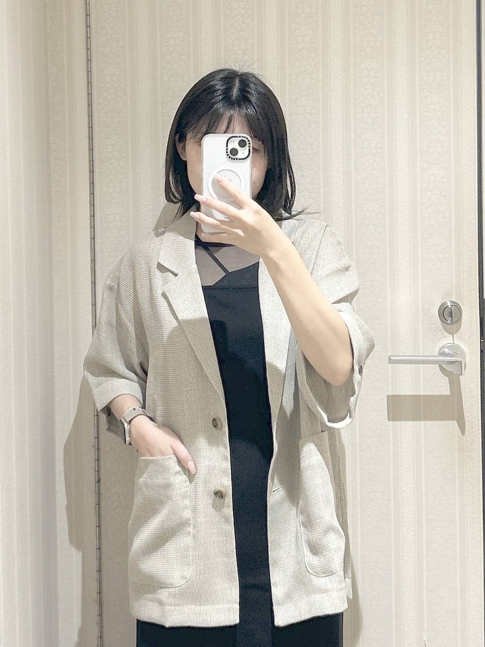 ホワイト系のパンプス、ベージュ系のテーラードジャケット、ブラック系のワンピースを着用したレディースの春コーディネートの3枚目の写真