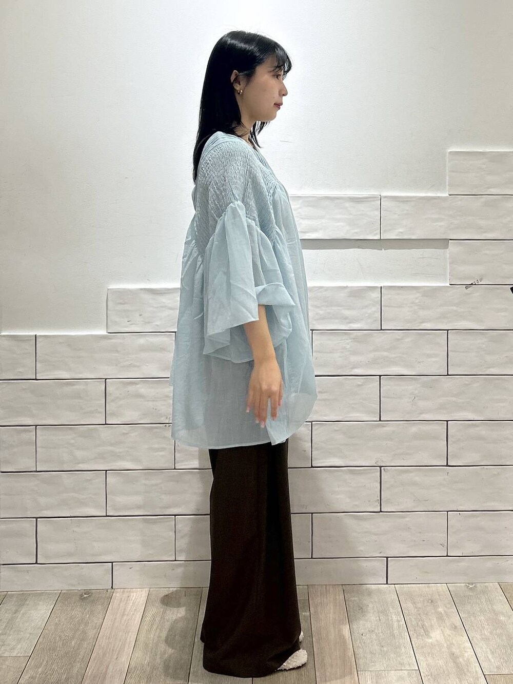 ブルー系のシャツ/ブラウス、ブラック系のショルダーバッグ、ホワイト系のパンプスを着用したレディースの春コーディネートの2枚目の写真