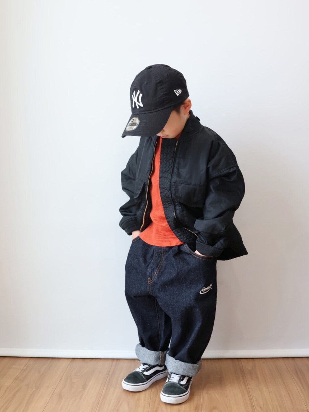 オレンジ系のトップス、ブラック系のジャケット/アウター、ブルー系のデニムパンツを着用したキッズの冬コーディネートの2枚目の写真
