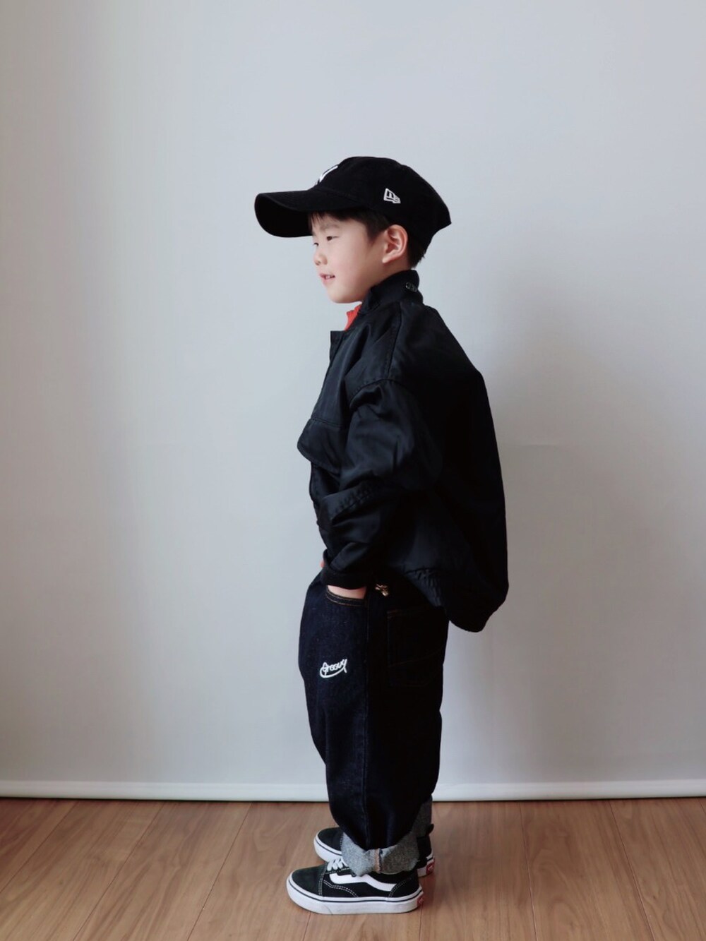 オレンジ系のトップス、ブラック系のジャケット/アウター、ブルー系のデニムパンツを着用したキッズの冬コーディネートの3枚目の写真