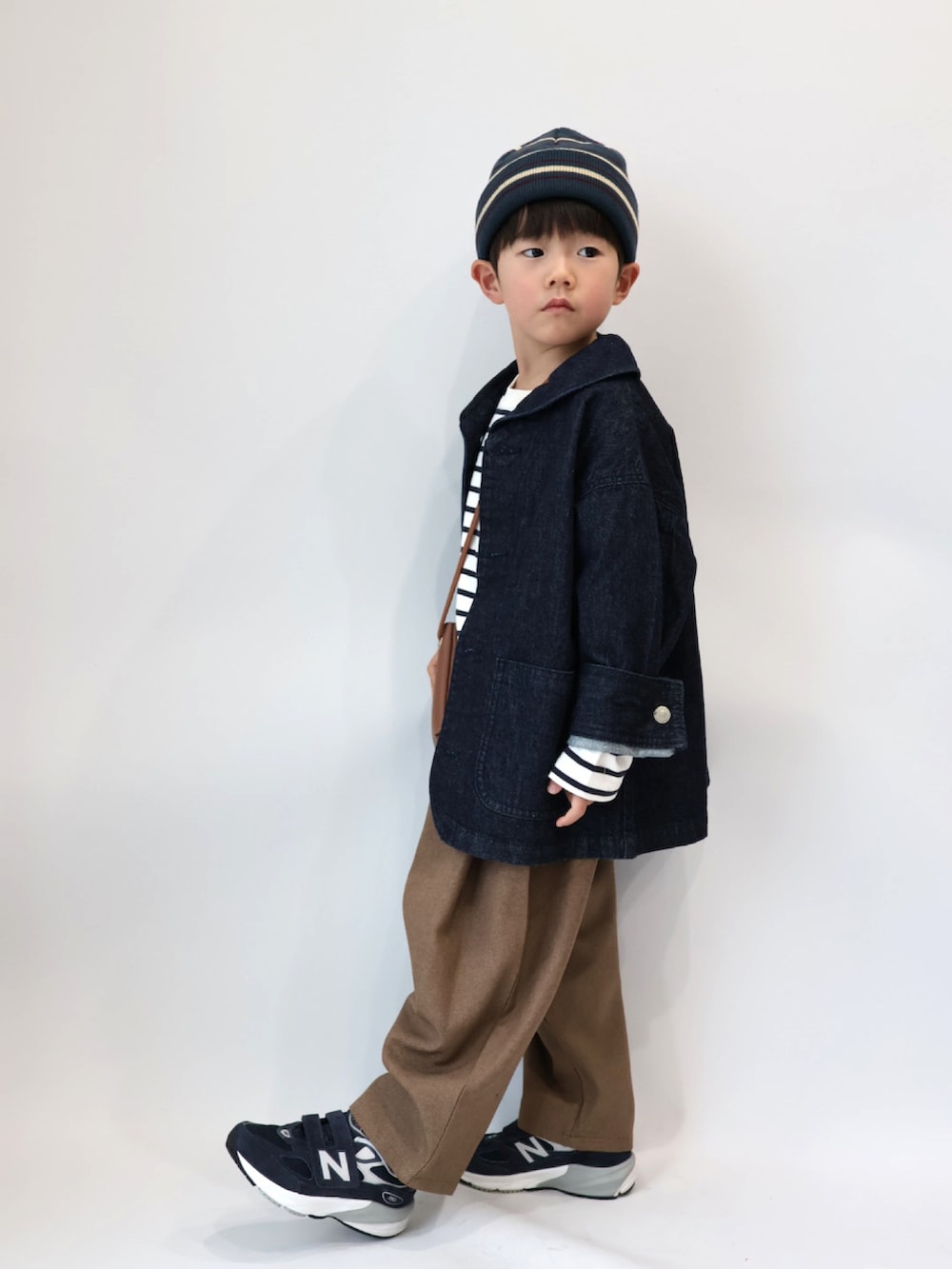 ブルー系のカバーオール、ブラウン系のショルダーバッグ、その他のトップスを着用したキッズの冬コーディネートの2枚目の写真