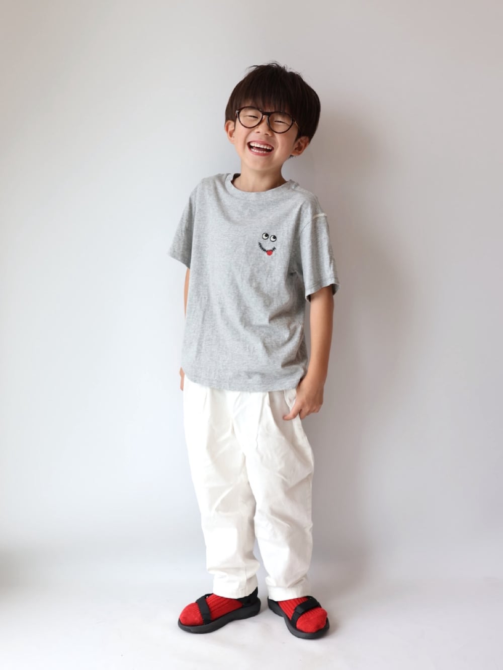 グレー系のトップス、ホワイト系のパンツ、ブラック系のサンダルを着用したキッズの夏コーディネートの2枚目の写真