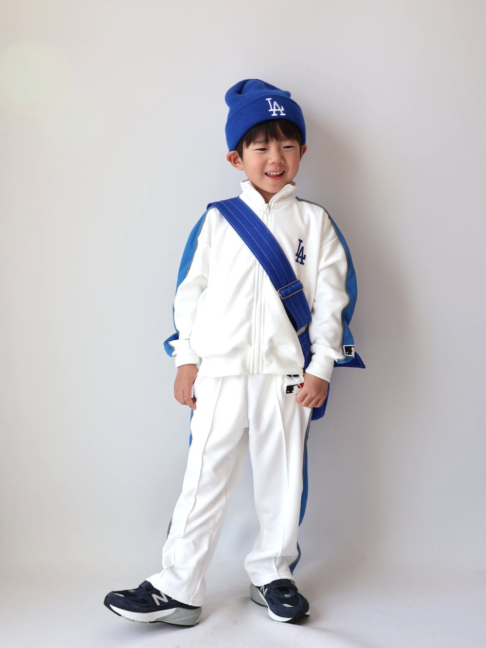 ベージュ系のジャージ、ベージュ系のスウェットパンツ、ブルー系のショルダーバッグを着用したキッズの冬コーディネートの2枚目の写真