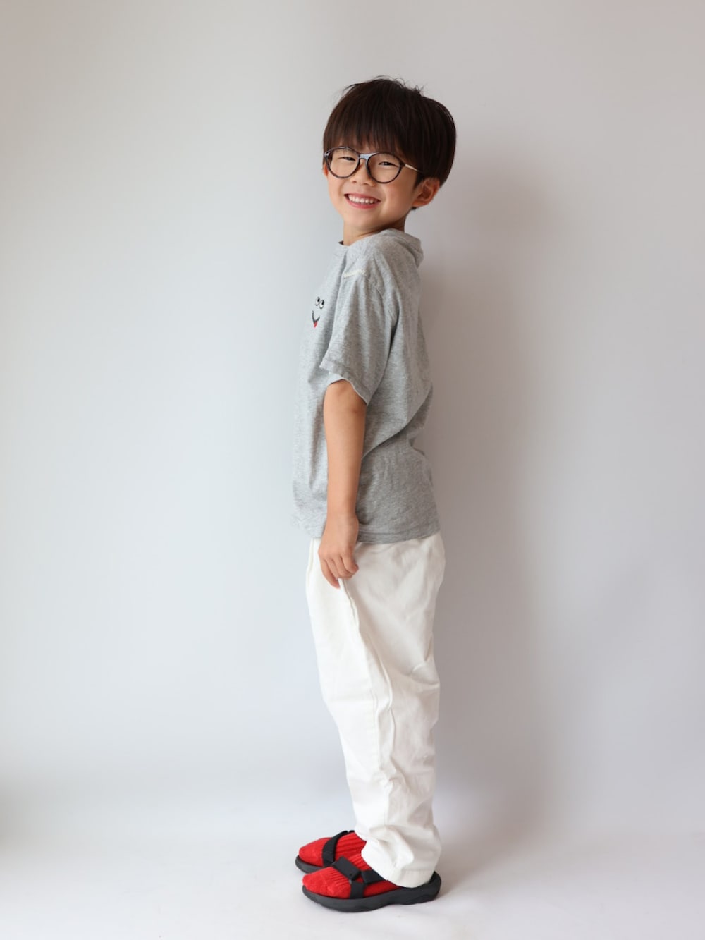 グレー系のトップス、ホワイト系のパンツ、ブラック系のサンダルを着用したキッズの夏コーディネートの3枚目の写真