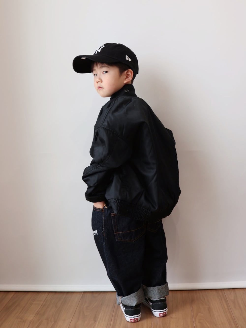 オレンジ系のトップス、ブラック系のジャケット/アウター、ブルー系のデニムパンツを着用したキッズの冬コーディネートの4枚目の写真