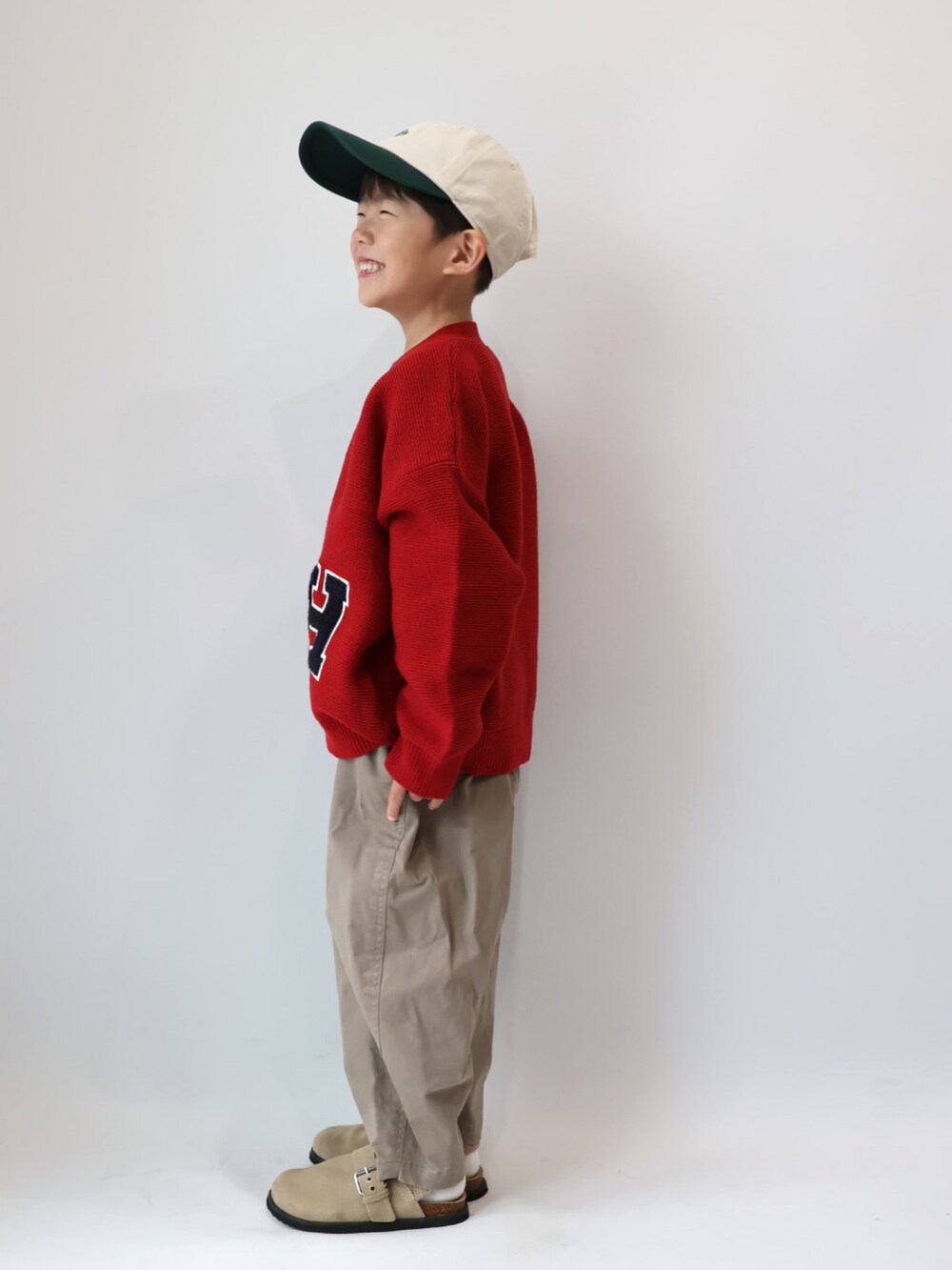 レッド系のカーディガン/ボレロ、グリーン系のTシャツ/カットソー、ブラウン系のチノパンツを着用したキッズの秋コーディネートの3枚目の写真