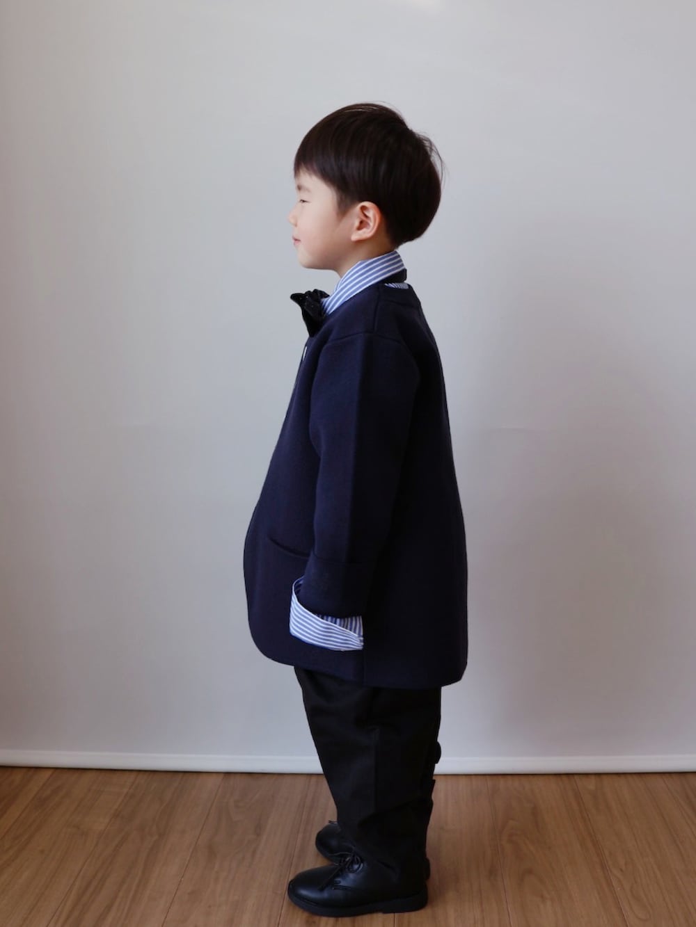 ブルー系のノーカラージャケット、ブルー系のシャツ/ブラウス、ブラック系のチノパンツを着用したキッズの冬コーディネートの4枚目の写真