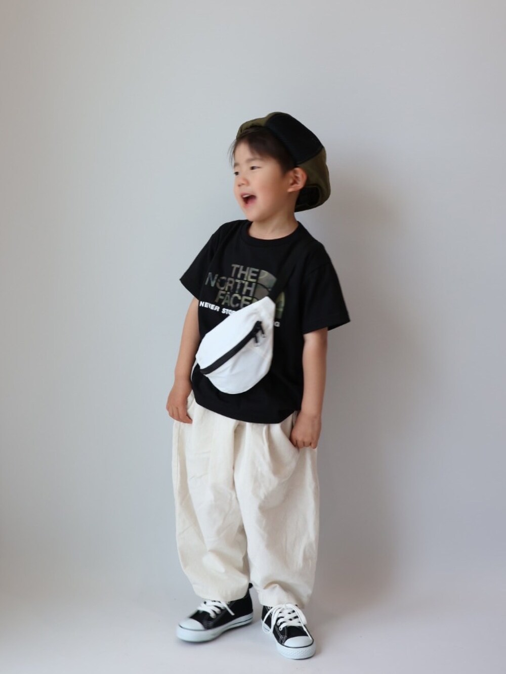 ホワイト系のボディバッグ/ウエストポーチ、ブラック系のTシャツ/カットソー、ホワイト系のその他パンツを着用したキッズの春コーディネートの2枚目の写真