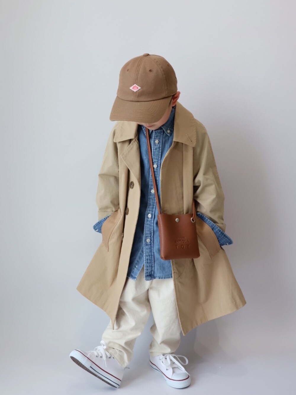 ベージュ系のステンカラーコート、ブラウン系のショルダーバッグ、ブルー系のシャツ/ブラウスを着用したキッズの春コーディネートの3枚目の写真