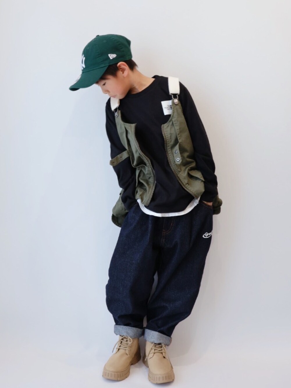 グリーン系のベスト、ブラック系のTシャツ/カットソー、ブルー系のデニムパンツを着用したキッズの春コーディネートの2枚目の写真