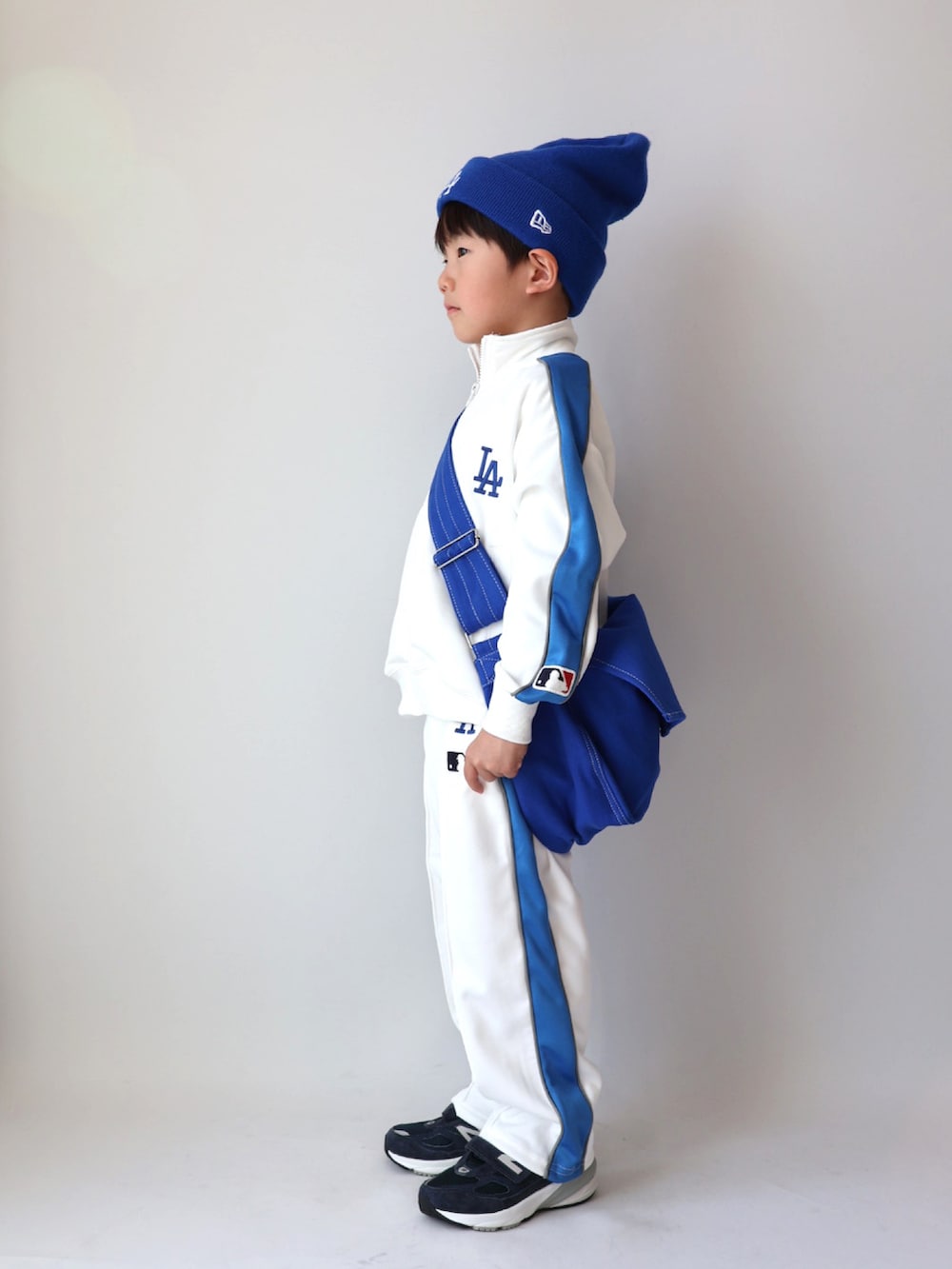 ベージュ系のジャージ、ベージュ系のスウェットパンツ、ブルー系のショルダーバッグを着用したキッズの冬コーディネートの3枚目の写真