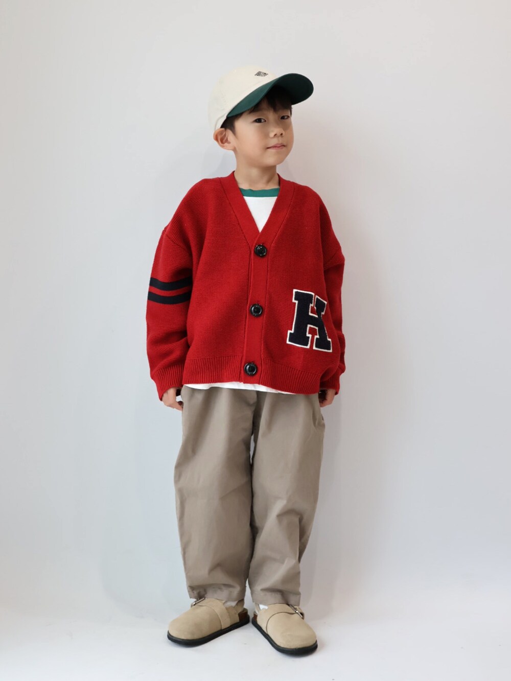 レッド系のカーディガン/ボレロ、グリーン系のTシャツ/カットソー、ブラウン系のチノパンツを着用したキッズの秋コーディネートの4枚目の写真