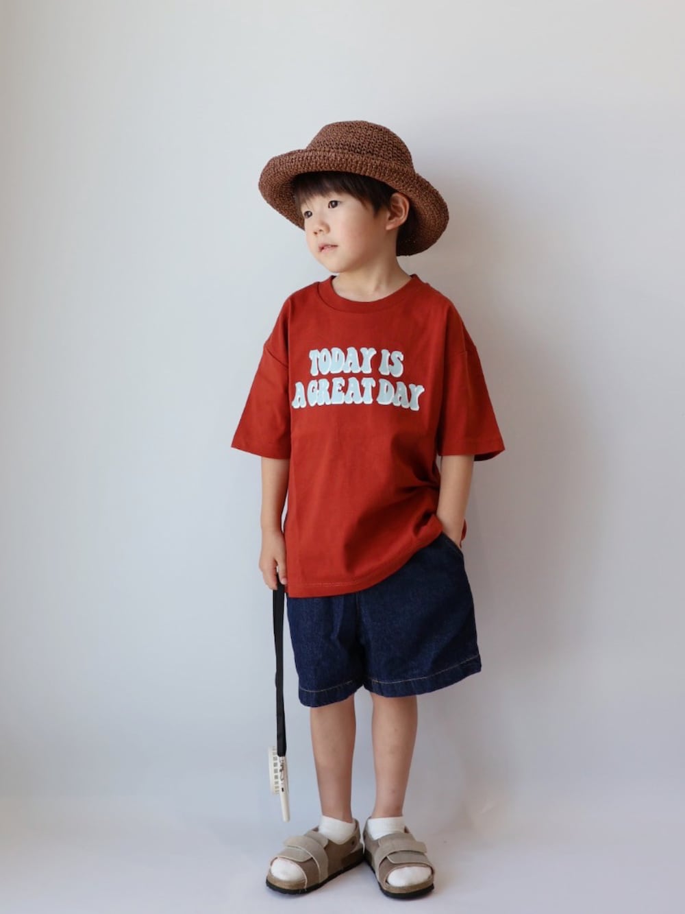 レッド系のTシャツ/カットソー、ブルー系のパンツ、ベージュ系のサンダルを着用したキッズの夏コーディネートの2枚目の写真