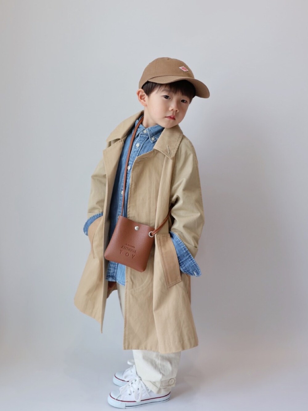 ベージュ系のステンカラーコート、ブラウン系のショルダーバッグ、ブルー系のシャツ/ブラウスを着用したキッズの春コーディネートの5枚目の写真
