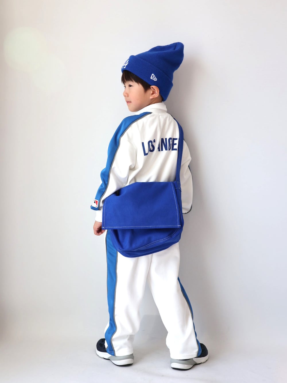 ベージュ系のジャージ、ベージュ系のスウェットパンツ、ブルー系のショルダーバッグを着用したキッズの冬コーディネートの4枚目の写真